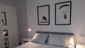 Ein Schlafzimmer mit einem Bett, zwei Nachttischen, einem Kleiderschrank und zwei gerahmten Bildern an der Wand.
