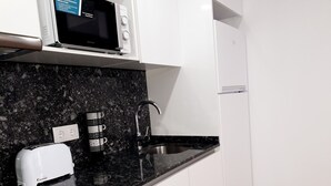 Eine Küche mit einer schwarzen Granitarbeitsplatte, einer Mikrowelle, einem Toaster und einem Spülbecken.
