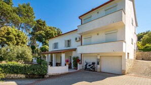 A two-story building with a covered porch, a scooter parked in front, and a stone wall. - Amazing apartment in Mundanije (Mundanije)