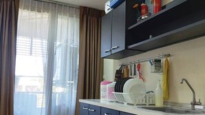 Cocina compacta con pileta, alacenas y una ventana con cortinas traslúcidas.