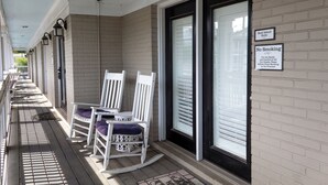 A hotel entrance with a covered porch, white rocking chairs, and a 'No Smoking' sign. - Prime downtown location, luxury condo getaway  (Wilmington)