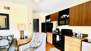 A compact living space with a kitchenette, a sofa, a patterned armchair, and a ceiling fan. - Prime downtown location, luxury condo getaway  (Wilmington)