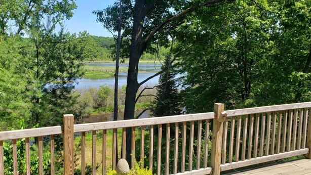 Eine Holzterrasse mit Blick auf einen Fluss und bewaldetes Gebiet.