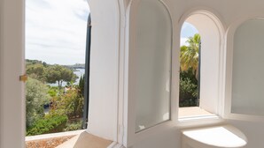 Una stanza con vista su alberi e un corpo d'acqua, attraverso finestre ad arco.