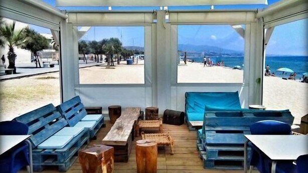 Una cabana sulla spiaggia con mobili in legno e vista sul mare.