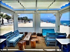 Una cabaña frente a la playa con muebles de madera y vista al mar.