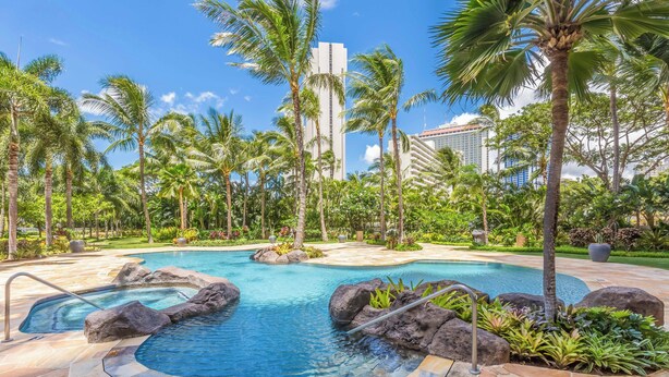 A pool area with multiple water features, surrounded by palm trees and a landscaped garden. - Ocean-City Views Glamorous Condo at The Watermark w/Parking & Full Kitchen (Honolulu)