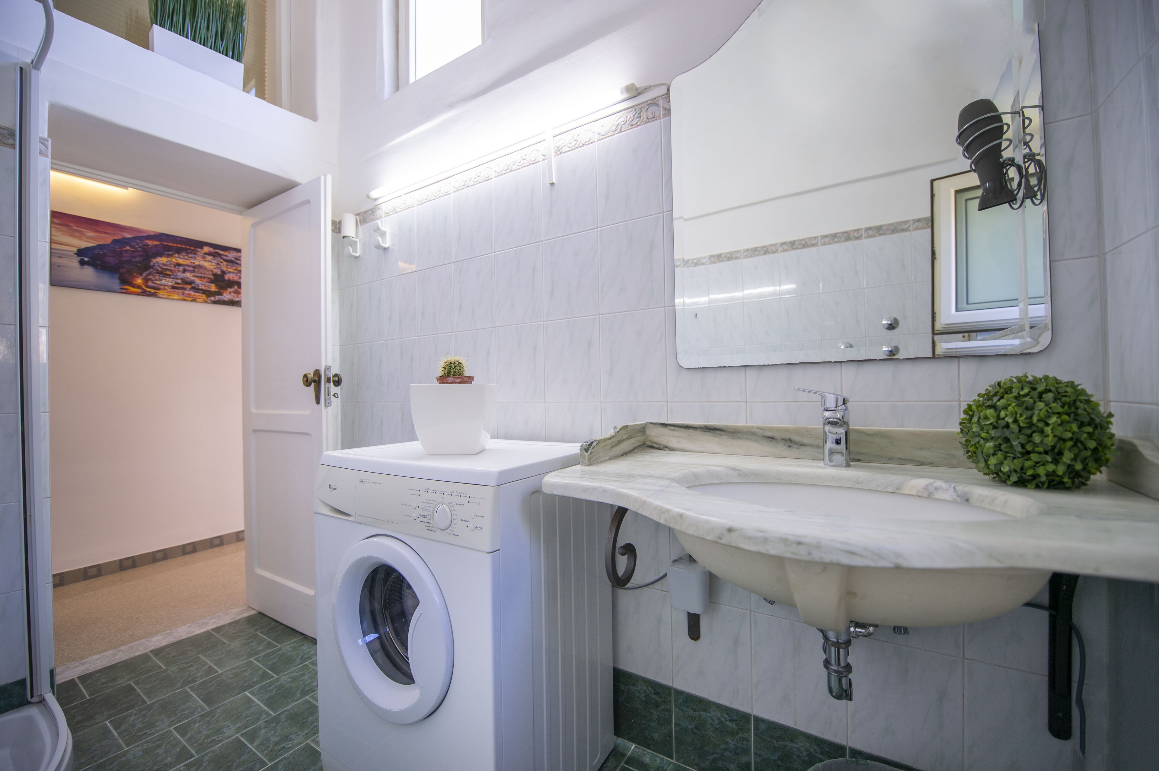 Een badkamer met een wasmachine, een wastafel en een spiegel.