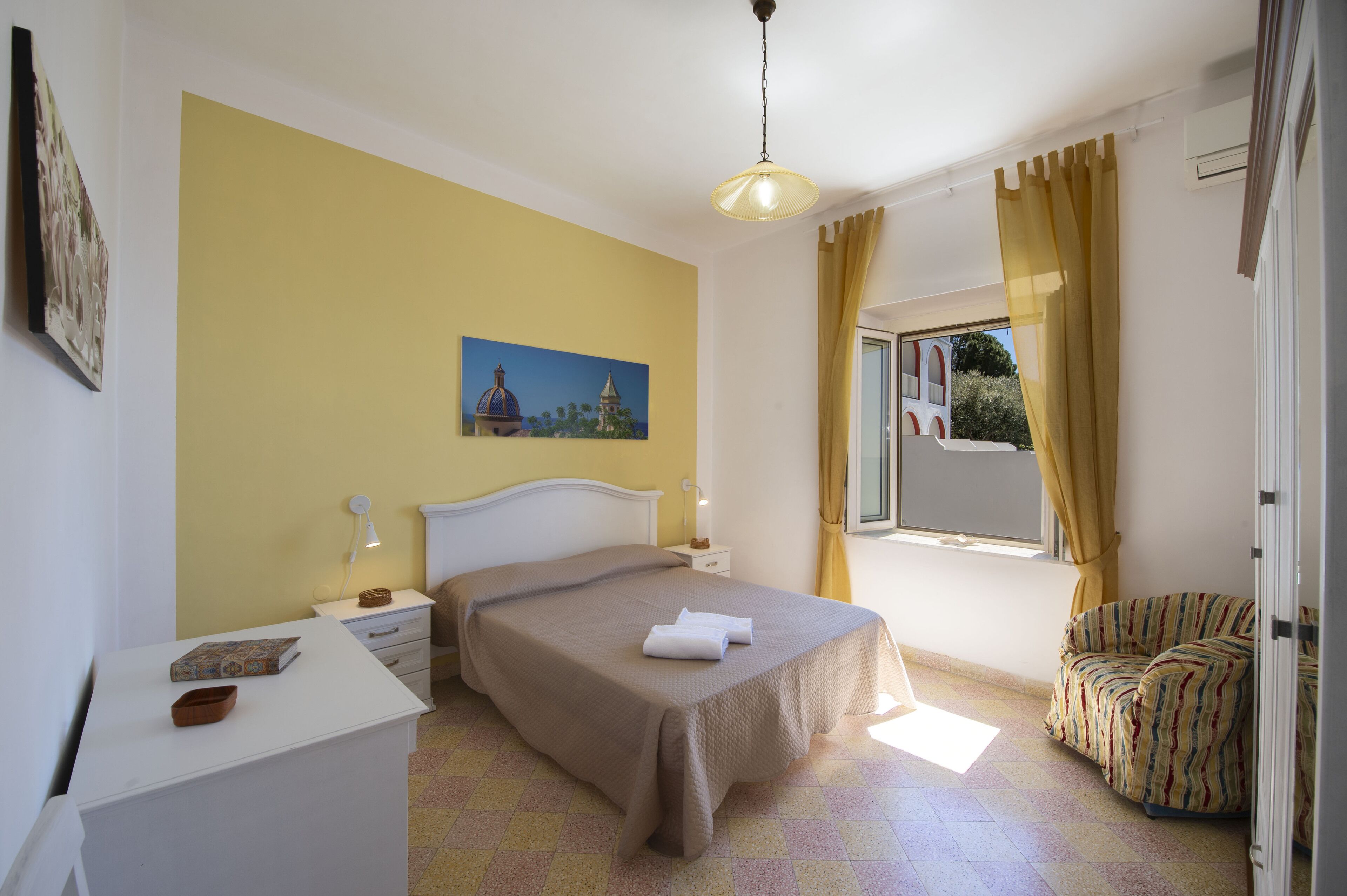 A bedroom with a bed, bedside table, lamp, and a window with curtains.
