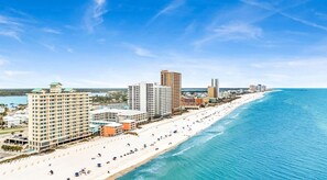 A coastal cityscape with a beachfront hotel, high-rise buildings, and a clear blue sky. - Crystal Shores1006 2 Bedroom Condo by RedAwning (Gulf Shores)