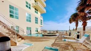 A pool area with lounge chairs and a hot tub, overlooking a body of water. - Crystal Shores1006 2 Bedroom Condo by RedAwning (Gulf Shores)