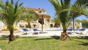 A poolside area with lounge chairs, palm trees, and a stone building with a pool. - Beautiful house for 6 people with pool, just a few minutes' drive to the beach (S' Horta)
