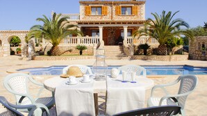 A two-story stone building with a pool in front. There are outdoor tables and chairs, and palm trees around. - Beautiful house for 6 people with pool, just a few minutes' drive to the beach (S' Horta)