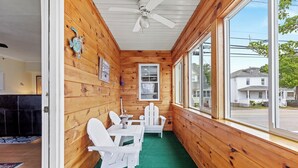 A wooden cabin with a dining area, a ceiling fan, and a view of the outside.