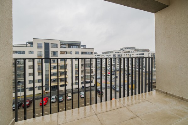 A balcony with a view of a multi-story parking garage and buildings in the background.