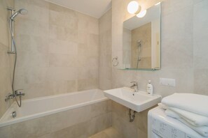 A modern bathroom with a bathtub, a sink, and a toilet.