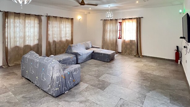 Uma sala de estar espaçosa com um sofá seccional, um ventilador de teto e um candelabro.