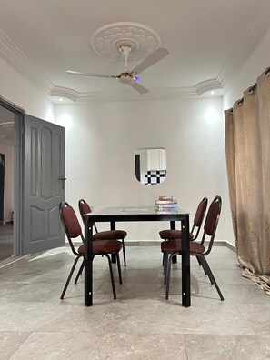 A dining room with a table and chairs, a ceiling fan, and a decorative mirror on the wall. - Charming 4-bed House in Kokrobite (Kokrobite)