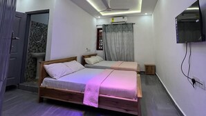 Quarto moderno com cama, ventilador de teto, TV e banheiro com pia e espelho.