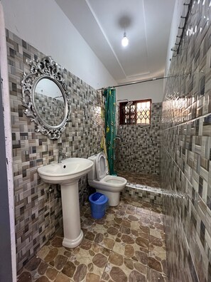 A bathroom with a tiled floor, a sink, a toilet, and a shower area. - Charming 4-bed House in Kokrobite (Kokrobite)