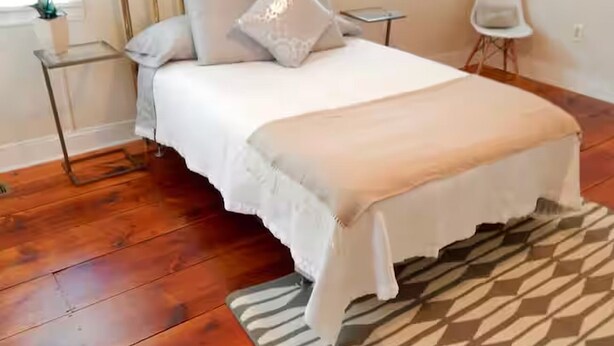 A bedroom with a bed, a bedside table, a chair, and a window.