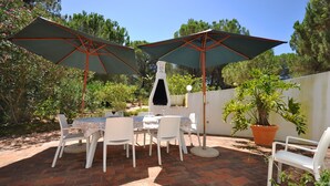 An outdoor patio with a brick floor, white chairs, a table, and two large umbrellas. - Fantastic outdoor area, private pool, Tennis Court & Golf Practice Facility (Faro)