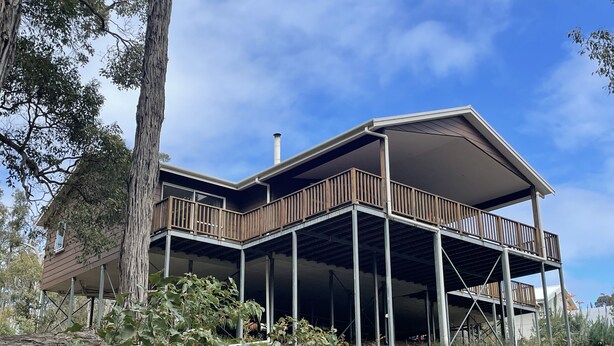 A two-story house with a wooden deck and a large chimney. - Blue Wren Retreat, Nannup - "Resting Place" (Nannup)