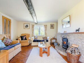A cozy living room with a fireplace, wooden furniture, and a stone wall.