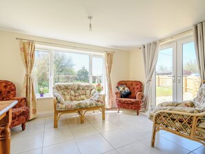 A spacious living room with a large window, a ceiling fan, and a wooden coffee table. - 3 bedroom accommodation in Cambridge, near Lower Cam (Cambridge, near Lower Cam)