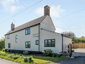 Una casa a due piani con un cartello che riporta 'Rathlin Cottage'.
