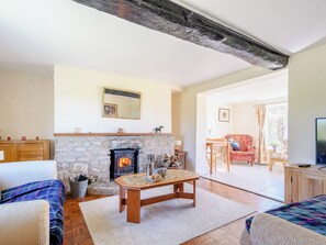 A living room with a stone fireplace, a wooden coffee table, and a sofa. - 3 bedroom accommodation in Cambridge, near Lower Cam (Cambridge, near Lower Cam)