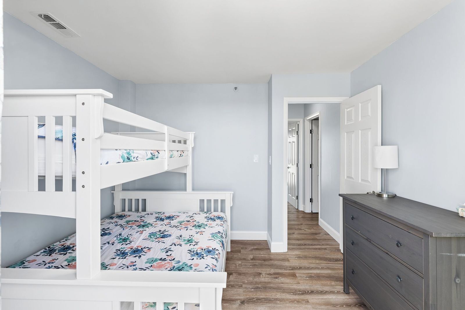 Un dormitorio con una litera, un aparador y una puerta que da a otra habitación.