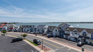Een kuststraat met rijtjeshuizen, een parkeerplaats en uitzicht op zee.