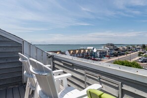A balcony with white chairs overlooking a coastal town and the sea. - Breezy Point Townhouse 3 BR/2BA with 4 Bay views (Ocean City)