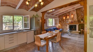 A spacious kitchen with a dining table, a refrigerator, and a stone fireplace.