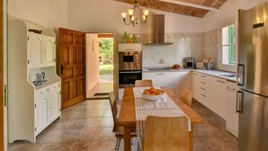 A kitchen with a dining table, wooden cabinets, a built-in oven, and a refrigerator.