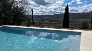 Une piscine rectangulaire à l’eau d’un bleu limpide, entourée d’une terrasse carrelée.