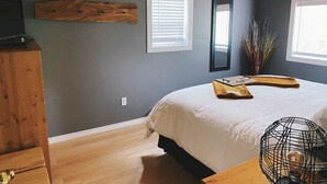 A bedroom with a bed, wooden headboard, a dresser, a mirror, and a window with blinds. - The Cabin on Grey Owl w/hot tub (Onanole)
