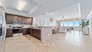 A spacious kitchen with modern appliances, a dining area with a view, and a balcony. - New Complex!  Lazy River/Slide, Beachfront! (Orange Beach)