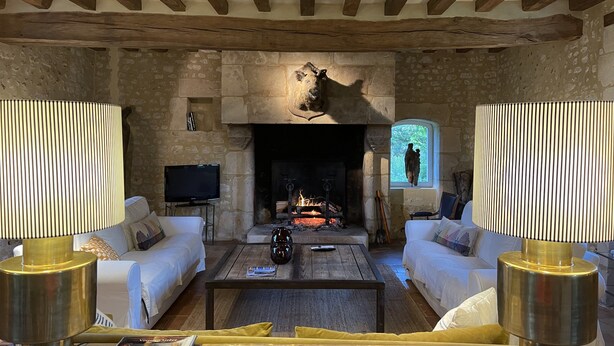 A rustic living room with stone walls, a fireplace, and a television. - 14-person family home in Perche with heated pool and tennis court (Rémalard-en-Perche)
