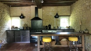 A rustic kitchen with a central island, wooden beams, stone walls, and two hanging pendant lights. - 14-person family home in Perche with heated pool and tennis court (Rémalard-en-Perche)