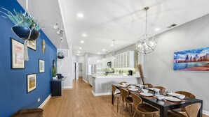 A modern kitchen with white cabinets, a central island, and a dining area with a table set for six.