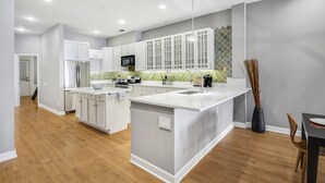 A modern kitchen with white cabinetry, a central island, and a microwave.