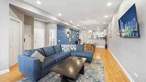 A modern living room with a sectional sofa, a coffee table, and a large painting on the wall.