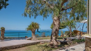 Una propiedad costera con un sendero pavimentado, un muro de piedra y vista al mar.