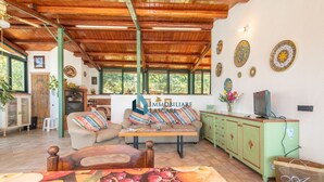 Una sala de estar acogedora con un sofá, una mesa de madera y un mueble verde. Hay platos decorativos en la pared y un letrero que dice 'IMMOBILIARE LASCARI'.