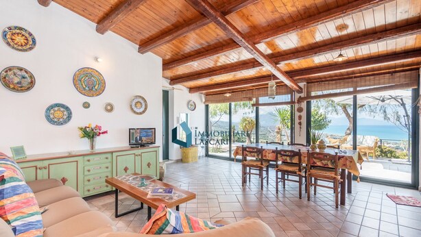 Amplia sala de estar con techo de madera, una mesa de comedor y vistas al mar.