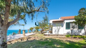 Una propiedad costera con un edificio blanco, pilares de piedra y vistas al mar.