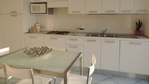 Une cuisine moderne avec des meubles blancs, une cuisinière à gaz, un évier et une table à manger avec des chaises.