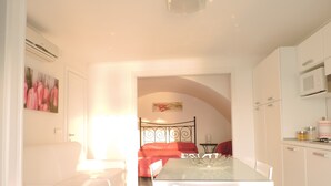 Une cuisine lumineuse et moderne, avec des meubles blancs et un coin repas comprenant une table en verre et des chaises blanches.